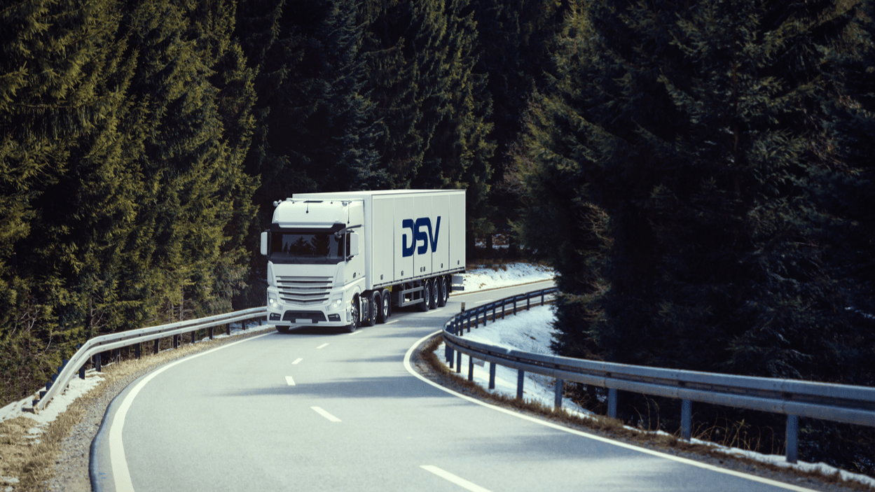 DSV lastebil kjører på vei gjennom skog.